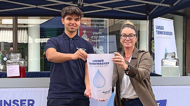 Pannekaukenfest Becher  Zwei MItarbeiter der Stadtwerke Schwerte halten symbolisch einen großen Trinkbecher in die Kamera